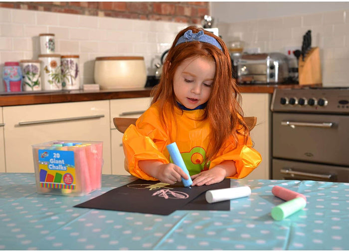 Child drawing on black paper with thick blue chalk next to a clear tub of 20 assorted large, colorful chalk sticks.