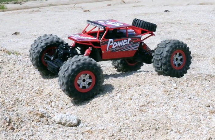 Red 2.4G 4WD amphibious RC crawler buggy car by dealonline.co.nz, showing rugged tires and waterproof design on a rocky surface.