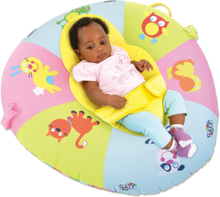 Baby reclining in a colorful inflatable ring with animal illustrations and a yellow fabric support seat.