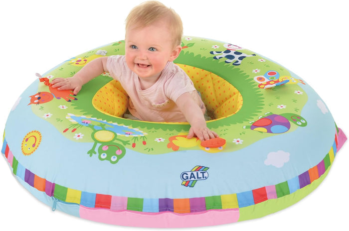 Smiling baby sits in a colorful inflatable ring decorated with farm animals and a rainbow-striped base.