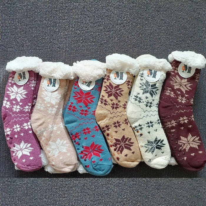 Four pairs of fuzzy women's slipper socks with grippers, featuring soft, warm material ideal for winter comfort.