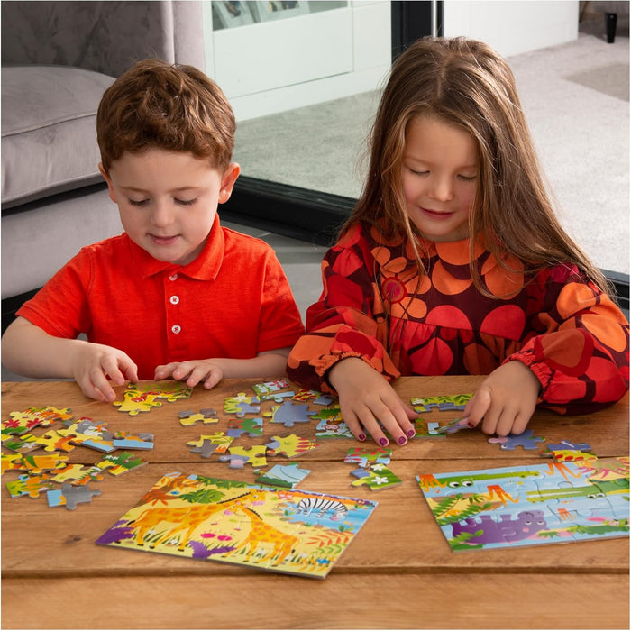 Two children assembling colorful jungle animal jigsaw puzzles with giraffe and hippo designs on a wooden table.