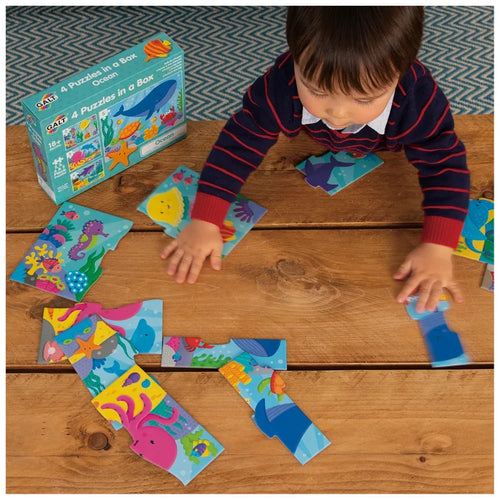 Child playing with colorful sea creature puzzle pieces on a wooden table next to a blue ocean-themed product box.