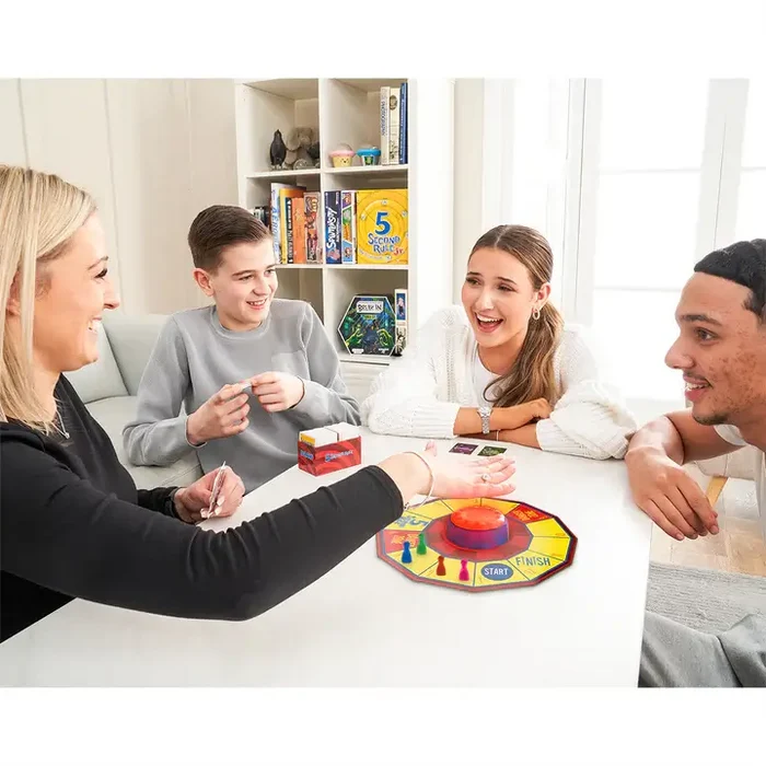 Four people play a board game with an octagonal board, a red central buzzer, and colorful pieces on a white table.