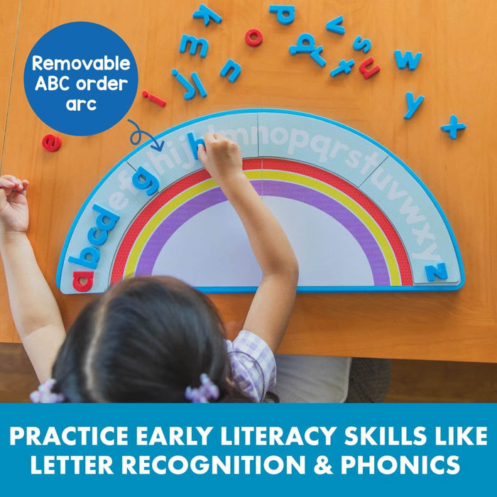 A child matches colorful magnetic letters to a rainbow-shaped alphabet arc mat on a wooden table.