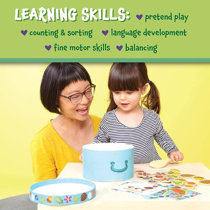 Woman and child play with a blue toy pot, wooden spoon, and round food tokens. Learning skills listed at the top.