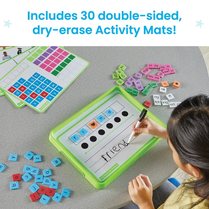 A child spells the word friend on a dry-erase activity mat using colorful letter tiles and a black marker.