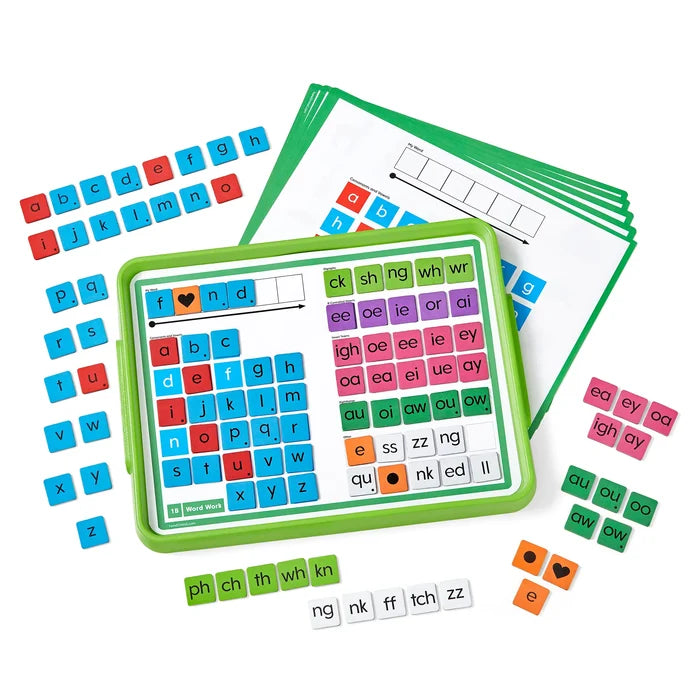 Green tray holding colorful letter tiles and digraphs, surrounded by loose tiles and word-building mats.