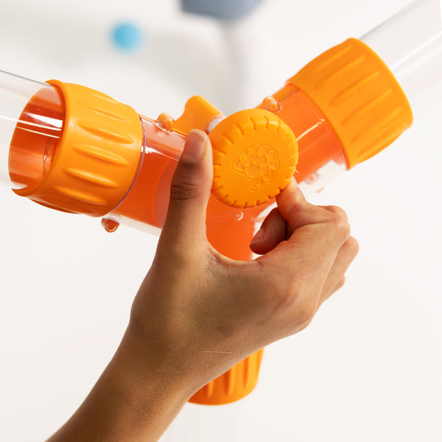 Hand turning an orange dial on a clear Y-shaped air flow diverter tube with orange connectors.