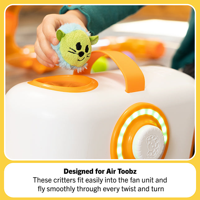 Child places a lime-green plush mouse toy into the opening of a white and orange fan unit with green lights.