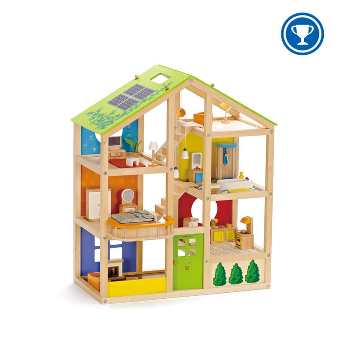 Three-story natural wood dollhouse with green solar-panel roof and vibrant, fully furnished rooms on every level.