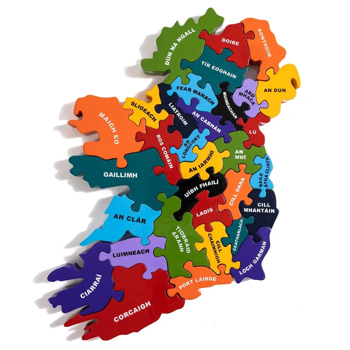 Colorful wooden jigsaw puzzle map of Ireland with individual county pieces labeled in Irish text.