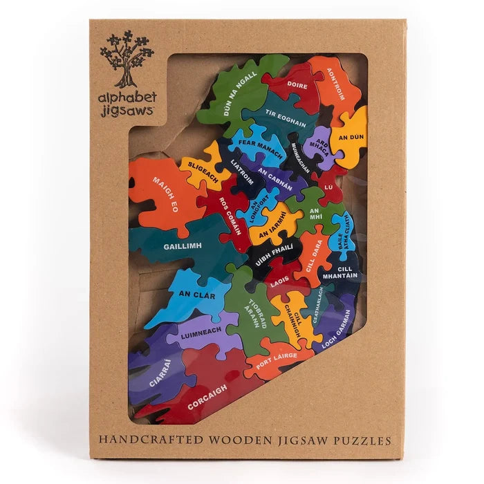 Colorful wooden jigsaw of Ireland's counties labeled in Irish, presented in a brown cardboard window box.