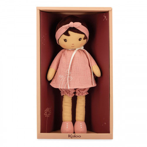 Soft rag doll with brown hair wearing a pink muslin dress and headband, presented in a pink and red gift box.