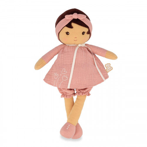 Soft plush doll with tan skin and dark hair, wearing a pink muslin dress, matching headband with bow, and pink shoes.