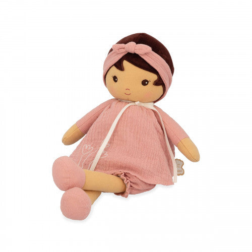 Soft tan doll with dark brown hair and a pink headband, wearing a pink muslin dress and bloomers, sitting.