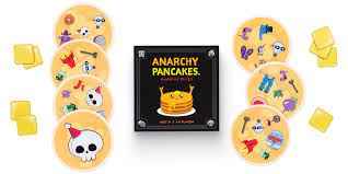 Square black game box with a pancake logo surrounded by round orange cards with icons and small yellow square tokens.