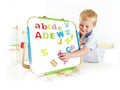 Child playing with colorful magnetic letters on a tabletop whiteboard with a natural wood frame and blue trim.