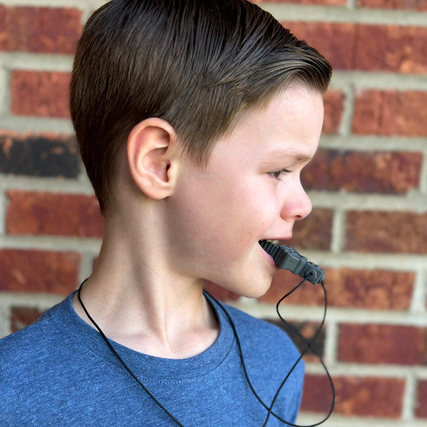 Profile of a boy biting a grey, robot-shaped textured sensory chew pendant on a black cord necklace.
