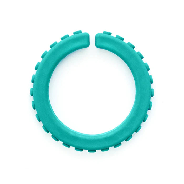 Teal open-circle chew bracelet with brick-like textured studs around the outer edge.