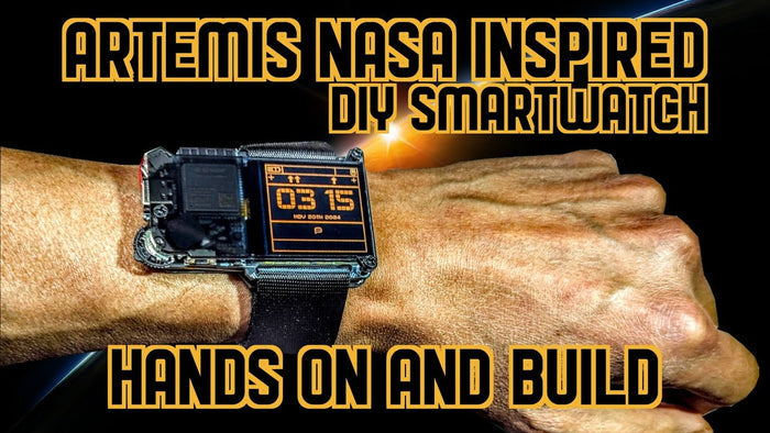 Industrial DIY smartwatch with exposed circuitry and orange digital screen worn on a wrist with a black strap.