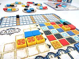 Azul board game close-up with colorful square tiles, patterned player boards, and circular factory coasters.
