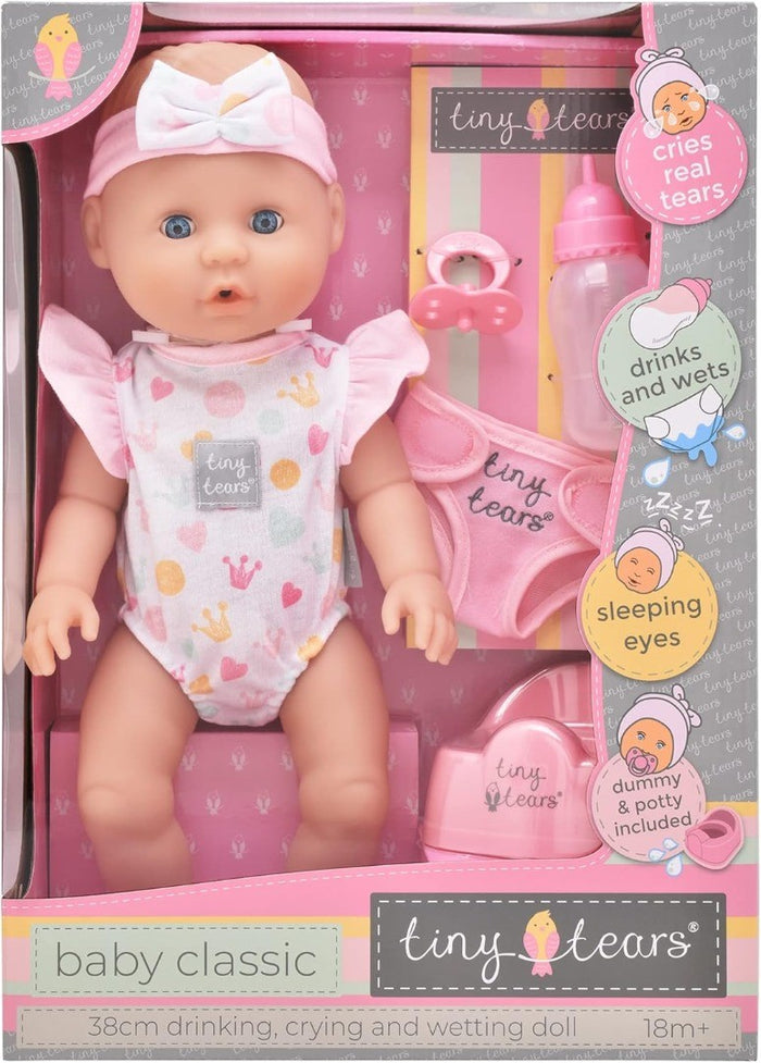 Baby doll with blue eyes and pink headband in box with accessories: pink bottle, potty, dummy, and diaper.