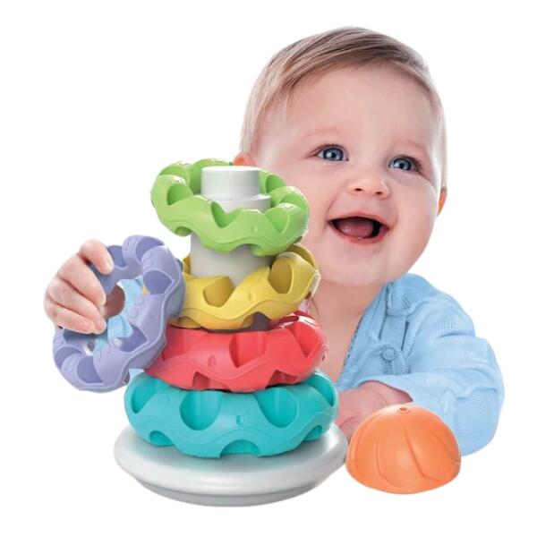 Smiling baby playing with colorful textured stacking rings in teal, red, yellow, green, lavender, and an orange cap.