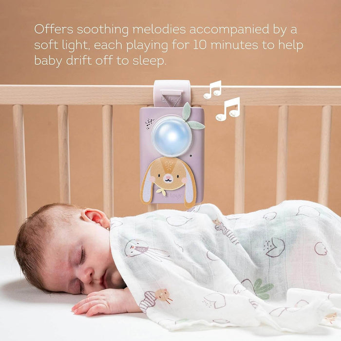 Purple bunny sound machine with a glowing blue light on a crib rail beside a sleeping baby in a patterned swaddle.