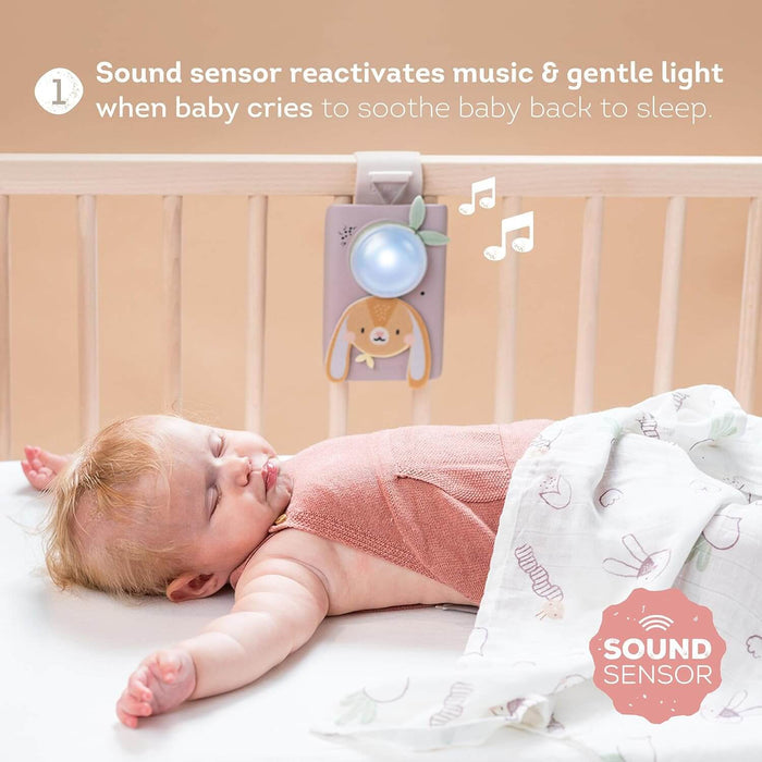 Purple bunny-themed sound machine with glowing light and music notes, attached to a crib with a sleeping baby.