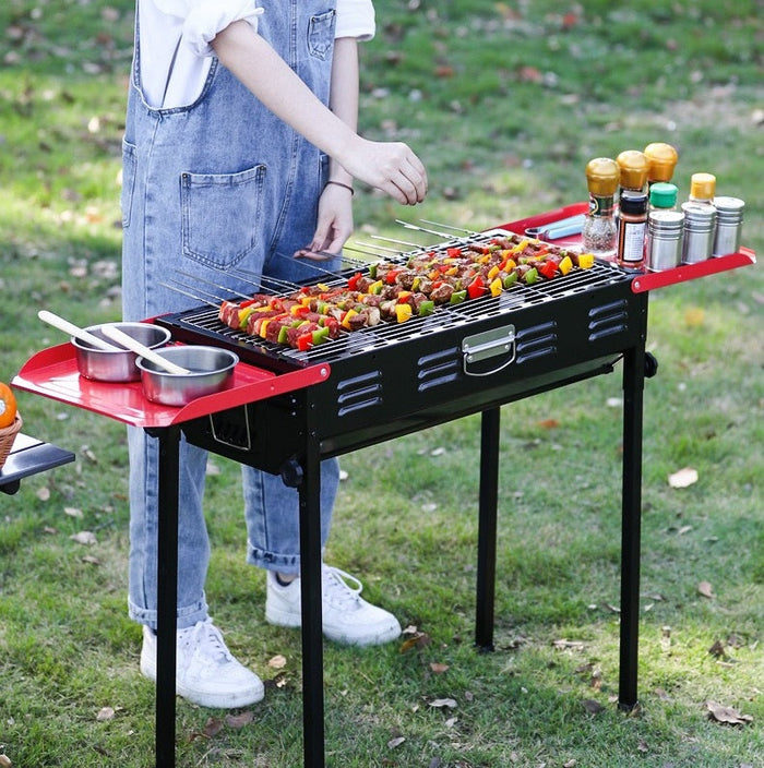 Portable folding barbecue charcoal grill for camping and picnics, with a compact design and handles for easy transport.