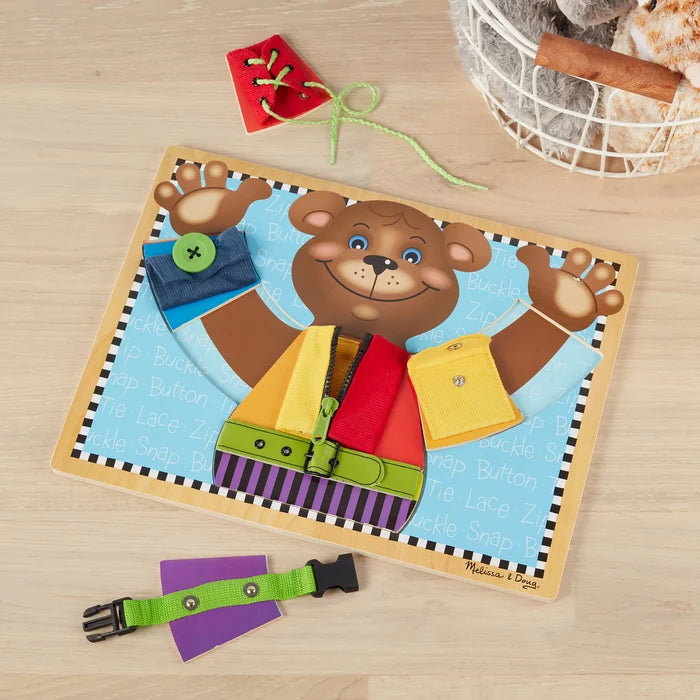Wooden bear puzzle with colorful fabric clothing tasks like a zipper, button, snap, buckle, and shoelace.