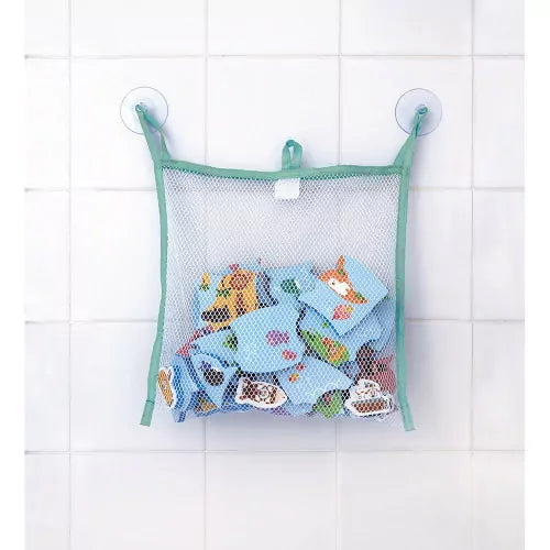 Green-trimmed mesh bag filled with blue foam bath pieces, hanging on a white tiled wall with two suction cups.