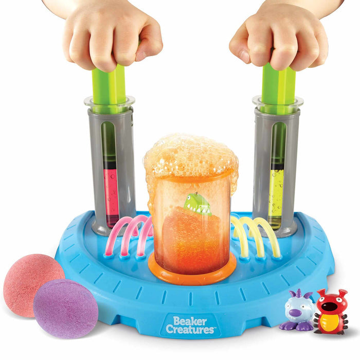 Science lab toy with plungers mixing colorful liquids into a bubbling orange beaker to reveal a green creature.