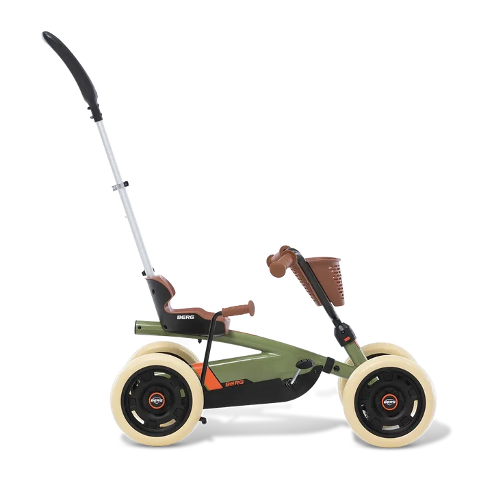 Olive green four-wheel pedal kart featuring a tall push handle, brown seat and basket, and chunky cream tires.