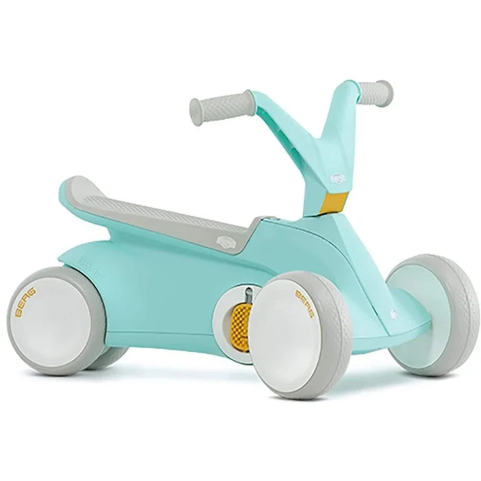 Mint green toddler ride-on toy with grey seat and handlebars, white wheels, and a retractable yellow side pedal.