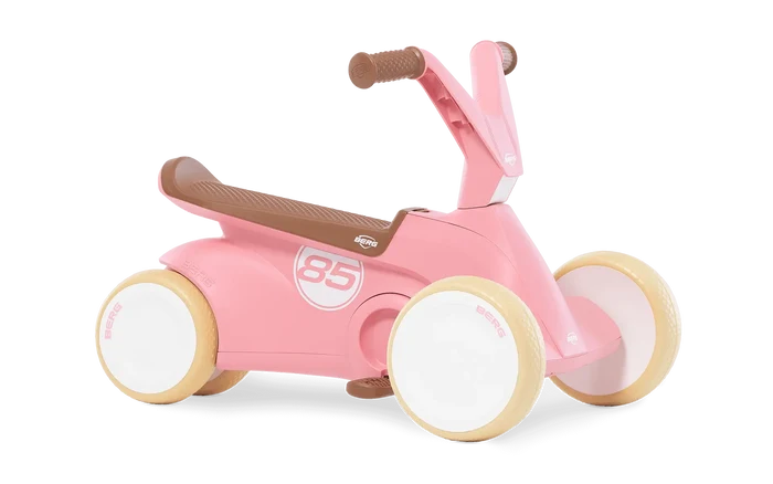 Pastel pink four-wheeled toddler ride-on with brown seat and grips, cream tires, and white number 85 on the side.