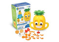 Yellow pineapple toy with green leaves and a toothy grin, shown with its box and colorful facial feature pieces.