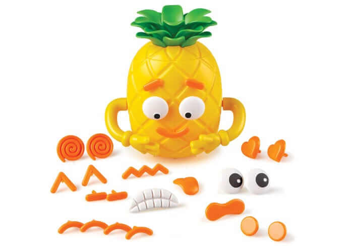 Yellow pineapple toy with green leaves and yellow arms, surrounded by orange and white facial feature pieces.