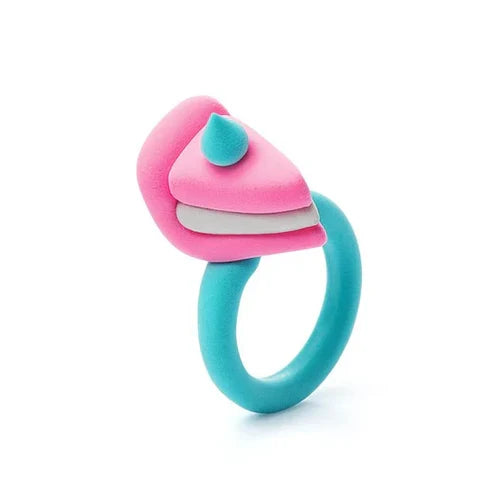 Teal toy ring topped with a pink and white layered cake slice and a small teal icing dollop.
