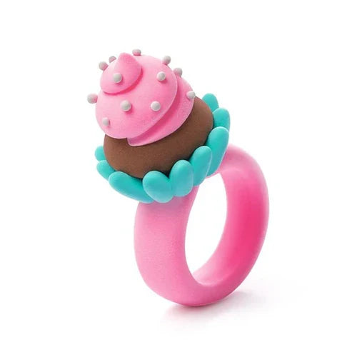 Pink toy ring featuring a miniature cupcake with pink frosting, white dots, brown cake, and a teal scalloped base.