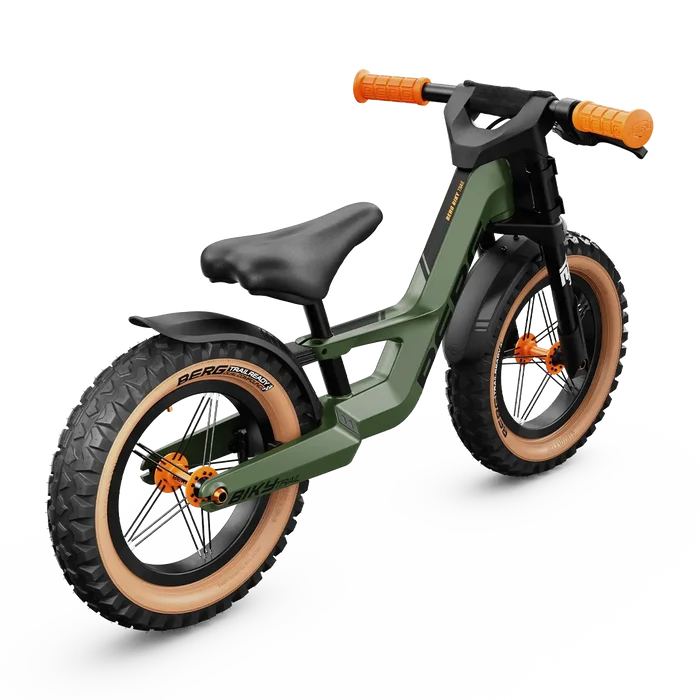Olive green kids balance bike featuring chunky off-road tires with tan sidewalls and bright orange grips.