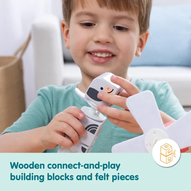Child connects black and white wooden cow blocks and soft white felt pieces to build a farm animal toy.