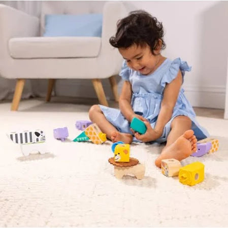 Toddler on a rug playing with colorful wooden animal blocks featuring a yellow lion and black and white zebra.