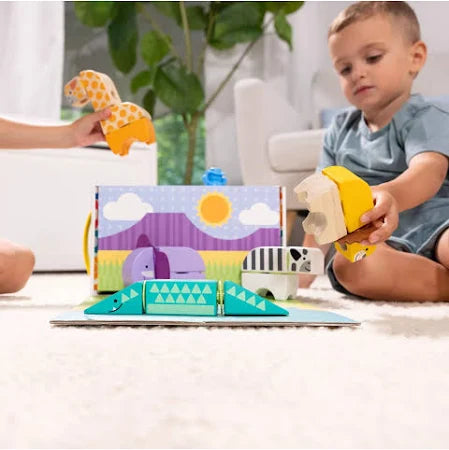 Toddler plays with colorful interlocking safari animal blocks, including a green crocodile, zebra, and themed box.