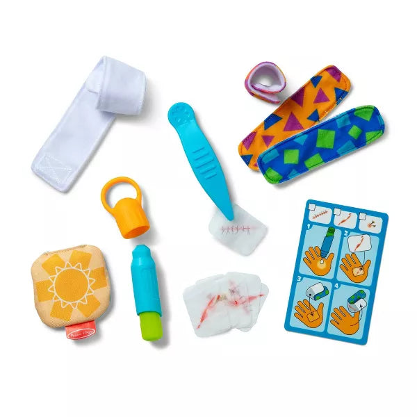 Toy first aid kit with colorful bandages, gauze with fake blood, a sun-print pouch, and a blue instruction card.