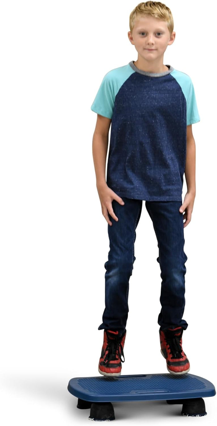 Boy stands on a blue, textured rectangular balance board with black rubber feet, wearing red and black sneakers.
