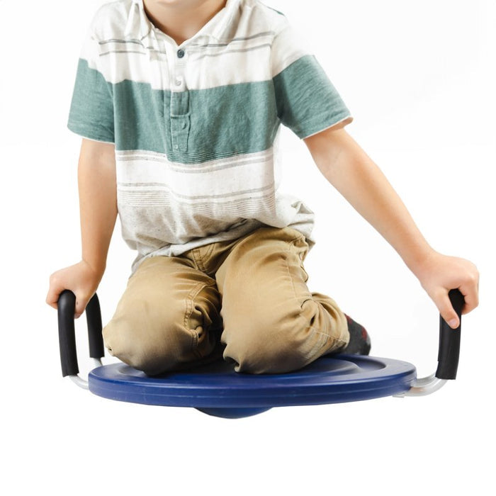 Child kneeling on a circular blue wobble board with black side handles for rocking and balance.