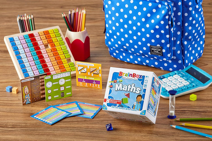 BrainBox Maths game box with colorful flashcards, multiplication grid, blue polka dot backpack, and blue calculator.