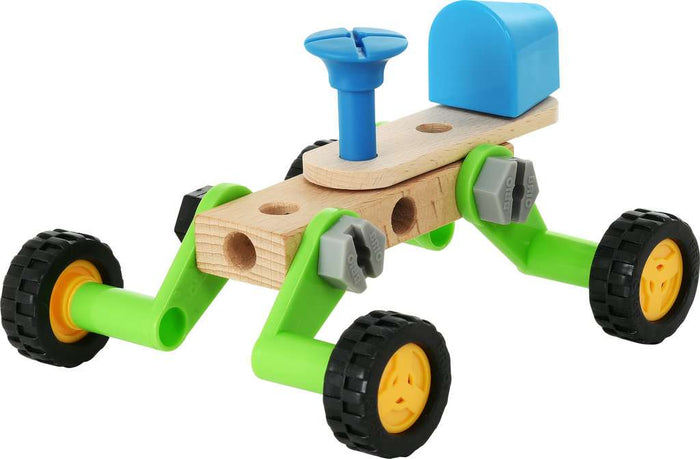 Toy construction vehicle made of wood planks, green plastic legs, black tires with yellow rims, and blue accents.